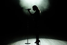 Black Silhouette Of Female Singer With White Spotlights In The Background