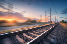 Railroad And Beautiful Blue Sky With Clouds At Sunset With Motion Blur Effect In Summer. Industrial Landscape With Railway Station And Blurred Background.  Railway Platform In Speed Motion. Concept