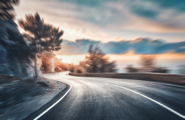 Wall Mural - mountain road at sunset with motion blur effect. asphalt road and blurred background with rocks, blu