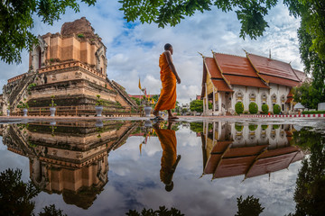 CHIANG MAI , THAILAND- AUGUST 2, 2019 : Novice is walking to study against Pagoda and reflection at Wat Chedi Luang Temple in Chiang mai, Thailand.