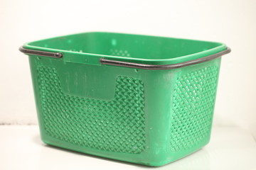 Green plastic shopping basket with black handles.