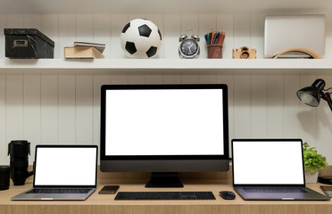 Stylish workspace with three computers blank screen background on wood table top, business concept. Mockup design with copy space.