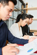 © DragonImages - Group of young business people sitting at the table and concentrating on their work at office