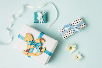 Wall Mural - Rocking horse toy with gift boxes; flowers and ribbon over blue backdrop