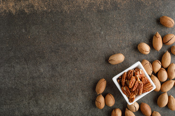 Wall Mural - Frame of pecan nuts on marble background. Square bowl of nuts in the corner