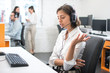 © Bojan - Young female call center operator with hands-free headset talking with client in office