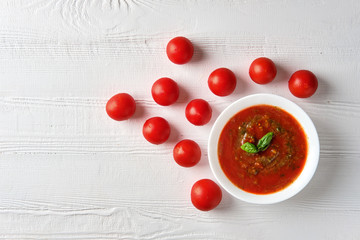 Tomato soup with basil, pepper, garlic, tomatoes and cucumber on wooden background. Spanish gazpacho soup.