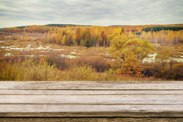 Empty wooden table with blurred picturesque autumn landscape of view from the hill to the lowland with forest and swamps. Mock up for display or montage products