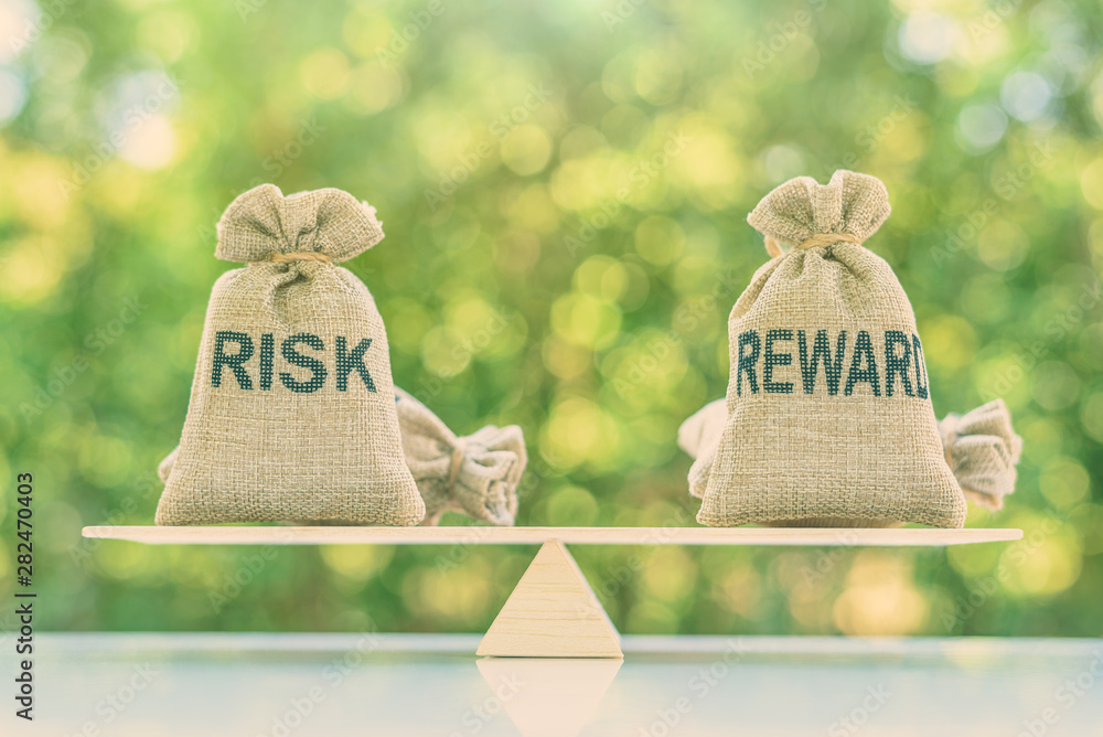 Risk reward ratio / risk management concept : Risk and reward bags on a basic balance scale in equal position, depicts investors use a risk reward ratio to compare the expected return of an investment - obrazy, fototapety, plakaty 