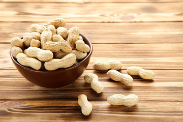 Peanuts in bowl on brown wooden table