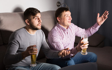 Canvas Print - Two men watching tv with anxious uncertainty