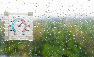 Canvas Print - rain drops and thermometer on wet window glass