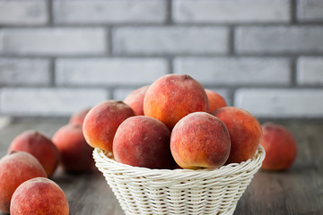 Ripe organic peaches in a white basket on a gray background.