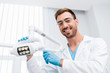 low angle view of cheerful dentist in glasses touching medical lamp and looking at camera