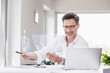 © Westend61 - Architect preparing presentation, sitting in office looking at foil plan