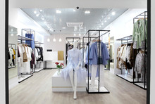 Interior Of Clothing Store .Bright Interior.Minimalistic Style.Clothes Hang On Hanger.Trendy Colors