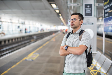 Young traveler in glasses standing at the train station.