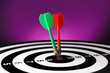 © New Africa - Arrows hitting target on dart board against purple background