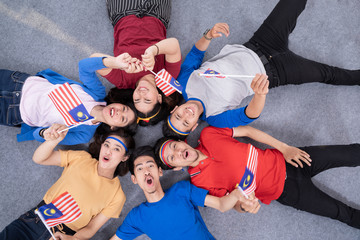 Wall Mural - excited asian young supporter holding malaysia flag over isolated background