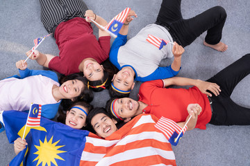 Wall Mural - excited asian young supporter holding malaysia flag over isolated background