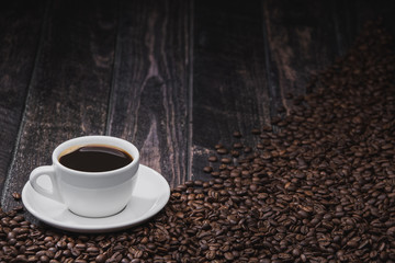 cup of coffee with beans on brown wooden background