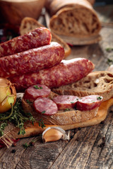 Dry-cured sausage with bread and spices on a old wooden table.