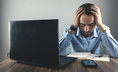 Wall Mural - Caucasian stressed businessman sitting and touching head in office.