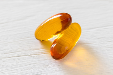 Close up view of fish oil capsule on white wooden background, vitamin and supplementa pill concept