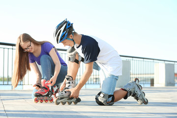 Wall Mural - Teenagers putting on roller skates outdoors