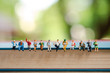 © Sunset Paper's - Miniature people, group of business people sitting on a book, doing activity and discussing ideas, society and teamwork concept.