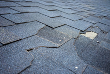 Close Up View Of Bitumen Shingles Roof Damage That Needs Repair.
