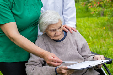 Wall Mural - Aged woman in a wheelchair with medical assistance