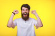 © Vulp - Bearded man is screaming with raised hand near yellow wall.