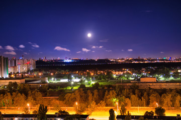 Canvas Print - Night city panorama with urban landscape and illuminated buildings under moon and night sky. Kiev