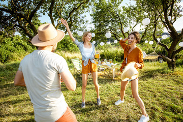 Young friends having fun, dancing in the beautifully decorated garden during a picnic on a sunny summer day