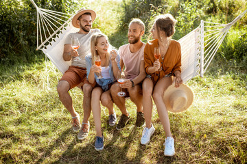 Portrait of a group of cheerful friends sitting together on the hammock, having fun outdoors during a summer days