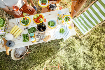 People having festive lunch in the garden with healthy food on the beautifully decorated table, top view