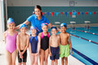 © Monkey Business - Portrait Of Female Coach With Children In Swimming Class Standing Edge Of Indoor Pool