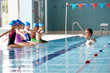 © Monkey Business - Male Coach In Water Gives Children Instructions In Swimming Lesson As They Sit On Edge Of Pool