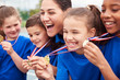 © Monkey Business - Children With Female Coach Showing Off Winners Medals On Sports Day