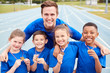 © Monkey Business - Portrait Of Children With Male Coach Showing Off Winners Medals On Sports Day