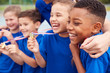 © Monkey Business - Children With Male Coach Showing Off Winners Medals On Sports Day