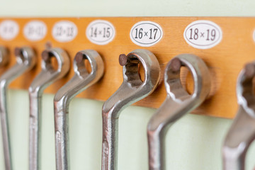 collection of spanners hanging on the wall on a wooden holder