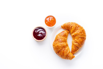 Wall Mural - Top view flatlay with fresh croissants served with jams and buter. Morning meal concept. White background