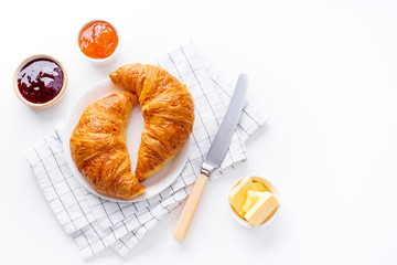 Wall Mural - Top view flatlay with fresh croissants served with jams and buter. Morning meal concept. White background