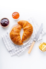 Wall Mural - Top view flatlay with fresh croissants served with jams and buter. Morning meal concept. White background