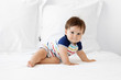 © Lisa Tichané - Serious baby sitting on white bed looking at camera