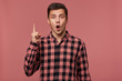 © timtimphoto - Young attractive wondered man wears in checkered shirt, looks at the camera with happy expression, shows thumb up, have the greatest idea! Stands isolated over pink background.