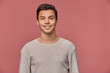 © timtimphoto - Photo of smiling handsome young guy wears in blank long sleeve, looks cheerful and glad, looks at the camera with happy expression, stands over pink background and smiling.