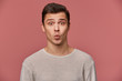 © timtimphoto - Portrait of handsome young cheerful man wears in blank long sleeve, looks at the camera with happy expressions,sens kiss, stands over pink background.